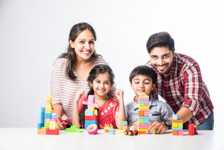 Cute little Indian kids playing colourful block toys with parents at home